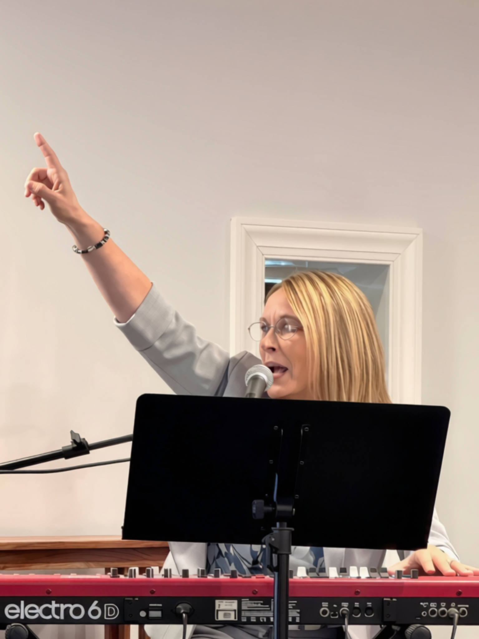 Rhonda Kilgore leading worship at the keyboard with her hand raised